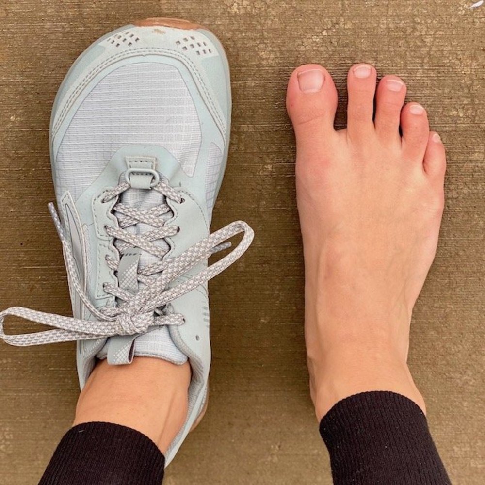 Wide-toe-box running shoe beside a bare foot